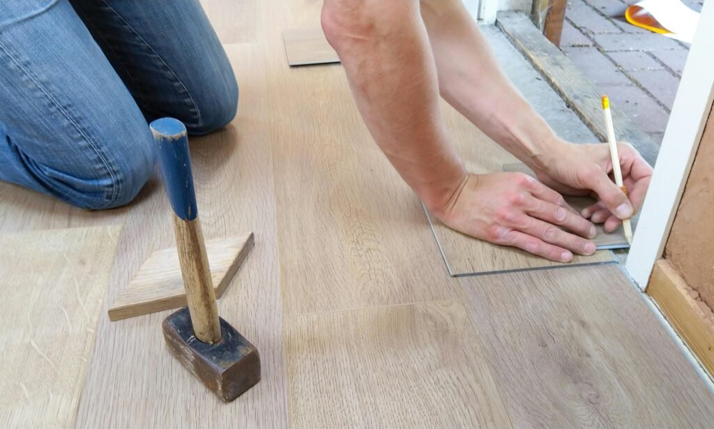 A craftsman carefully measures and marks wooden floor panels for precise installation.